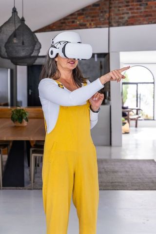 Senior woman exploring virtual reality with vr headset in modern open-plan home