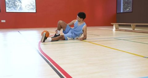 Male Basketball Player Tying Sneaker on Indoor Court