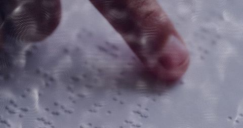 Pressing fingertip on textured surface with halftone dot pattern and macro detail