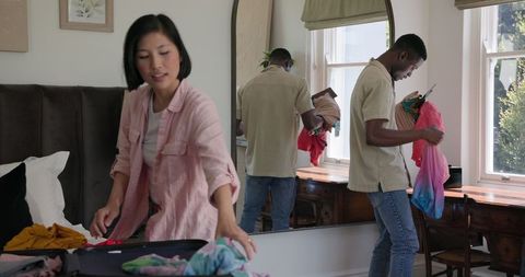 Couple Packing for Travel with clothes in Modern Bedroom