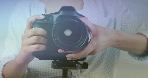 Photographer adjusting dslr camera on tripod with artistic flare