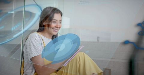 Smiling young woman studying with holographic interface on office stairs