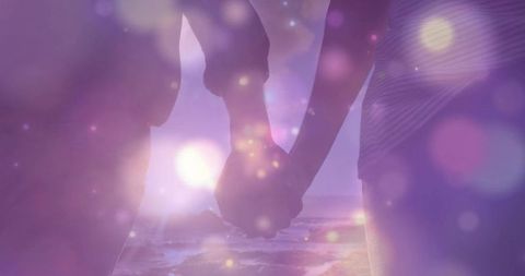 Couple Holding Hands on Sunset Beach with Soft Bokeh Lights