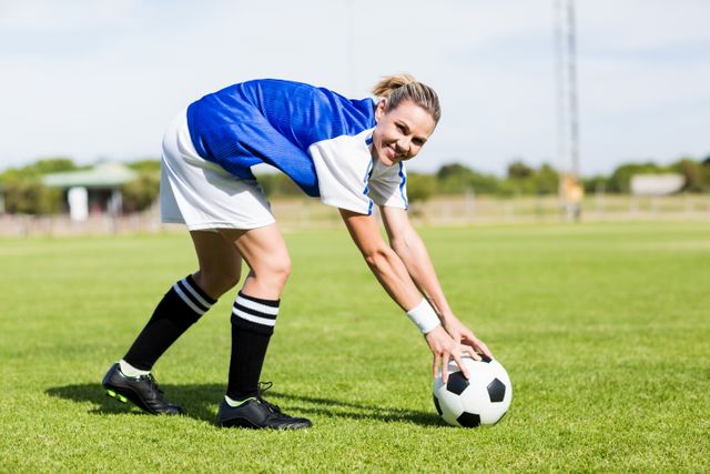 Portrait of female football player keeping a ball on the field