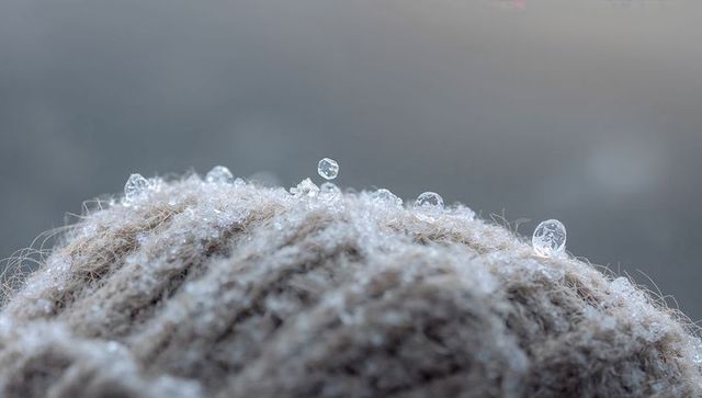 Macro view of icy crystals on ribbed wool beanie showing frost detail and knit texture