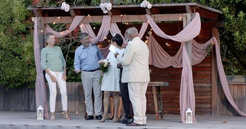 Senior diverse couple celebrating with friends in decorated garden