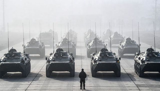 Soldier standing before armored vehicle formation on hazy parade ground