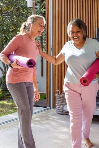 Senior Women with Yoga Mats Embracing Friendship and Wellness