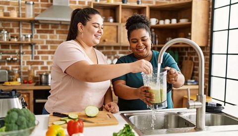 Making green smoothie together while rinsing blender in bright rustic kitchen