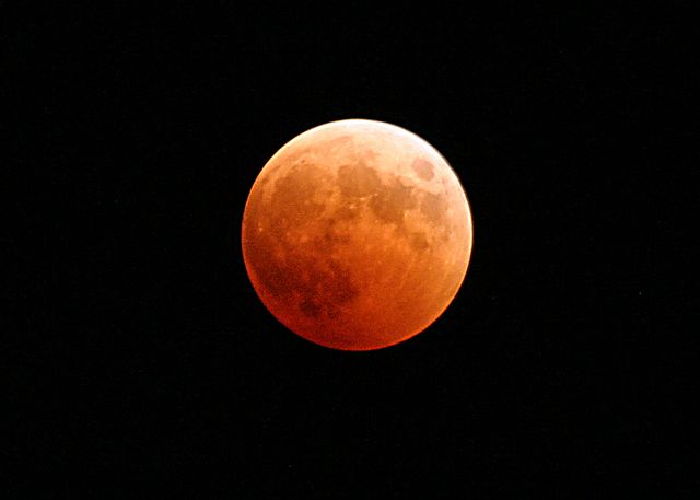 Red Moon appearing during lunar eclipse, casting an eerie red glow against the black night sky. Ideal for astronomy enthusiasts, educational materials on lunar phenomena, and articles discussing celestial events. Suitable for use in calendars, science blogs, and space-themed presentations.