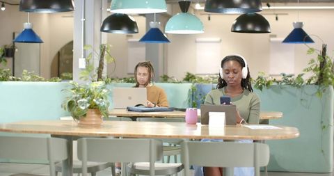 African American Coworkers Working in Modern Coworking Space with Laptops and Headphones