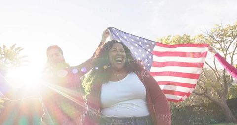 Joyful woman celebrating with american flag in sunlit park with lens flare and greenspace