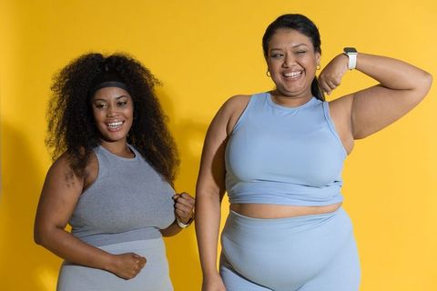 Confident diverse women flexing in colorful activewear on vibrant yellow background