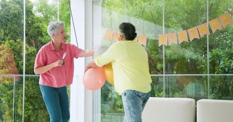 Senior Lesbian Couple Cleaning After Birthday Celebration