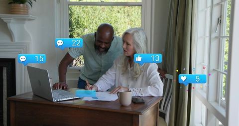 Senior couple reviewing finances and monitoring social media engagement at home desk