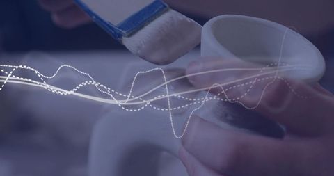Hand glazing porcelain cup with brush and waveform overlay for artisan branding