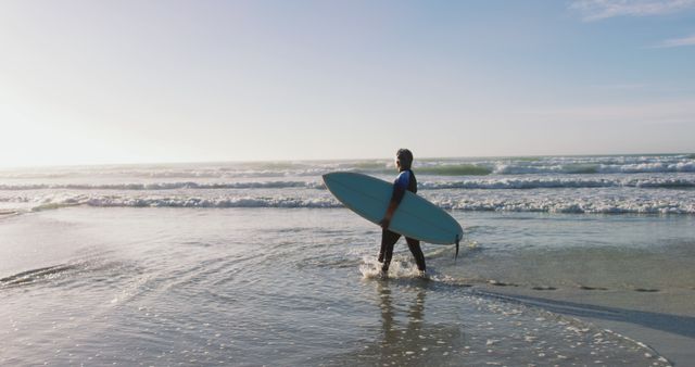 Senior african american woman walking with a surfboard at the beach. healthy outdoor leisure time by the sea.