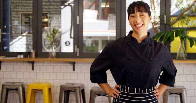 Smiling Female Chef in Black Uniform Standing in Modern Restaurant - Download Free Stock Images Pikwizard.com