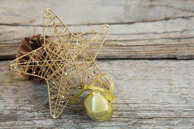 Christmas bell, pine cone and star on wooden plank during christmas time