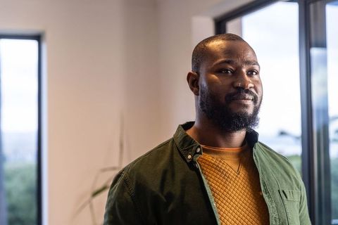 African American professional standing in modern office wearing mustard knit sweater