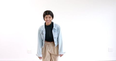 Young woman smiling in denim jacket against white background