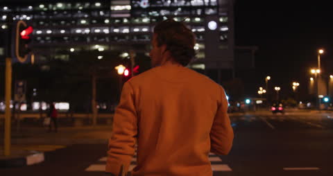 Man Walking in City at Night Using Smartphone