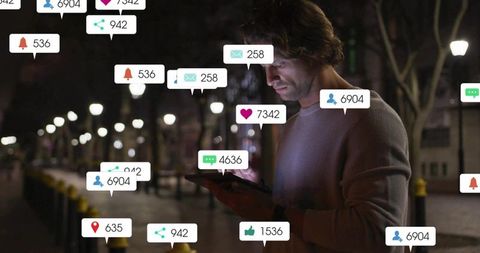 Mid adult man holding tablet viewing social notifications night urban street