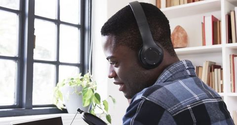 Focused content creator speaking into microphone with headphones at desk