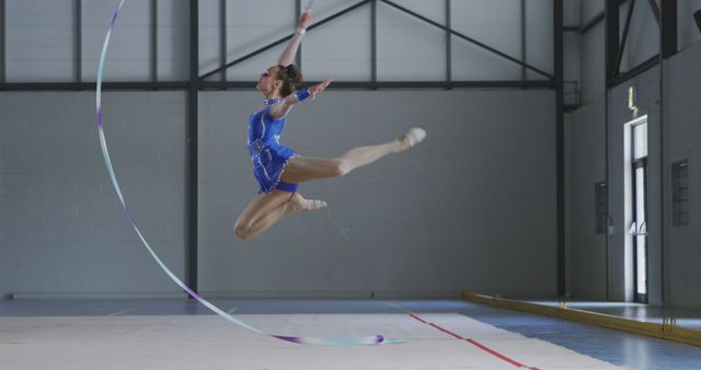 Gymnast performing rhythmic gymnastics with ribbon in mid-air indoors - Download Free Stock Images Pikwizard.com