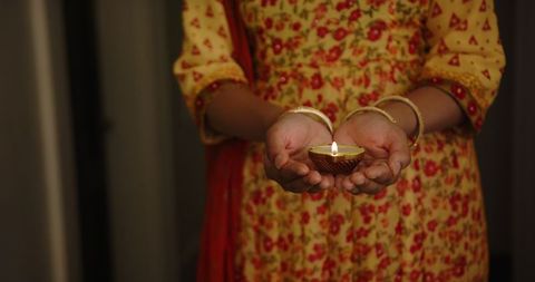Woman Holding Lit Diya for Diwali Celebration Illuminated with Traditional Warmth