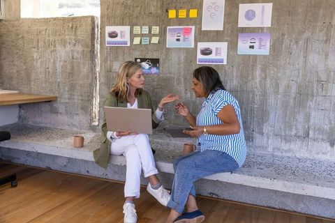 Female Coworkers Collaborating and Brainstorming in Modern Office Lounge