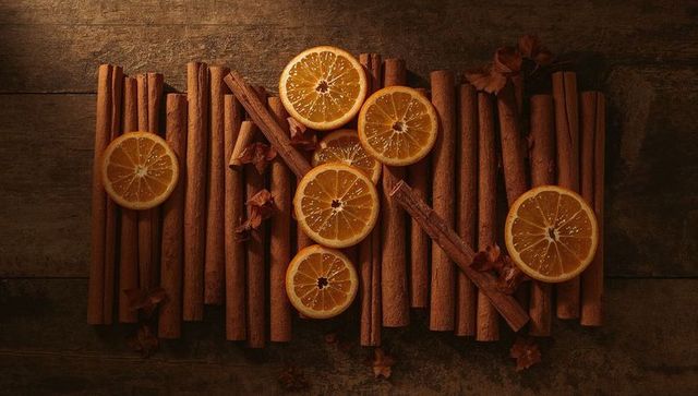 Arranging cinnamon sticks and dried orange slices with star anise on rustic wood flatlay