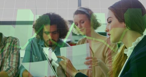 Business team analyzing data with tablet and printed reports overlaid with green charts