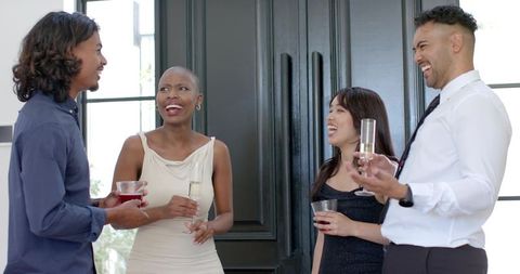 Diverse adults laughing, networking with champagne and cocktails in elegant foyer reception