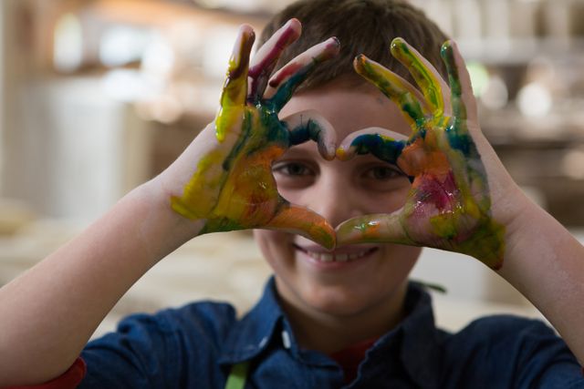 Boy gesturing with painted hands at pottery workshop