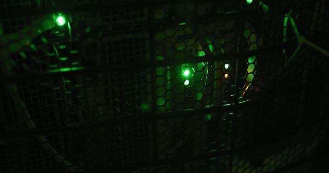 Depicts close up view of an illuminated server rack with green LED lights inside. Useful for illustrating technology concepts, highlighting data center environments, and showcasing telecommunication networks and IT infrastructure.
