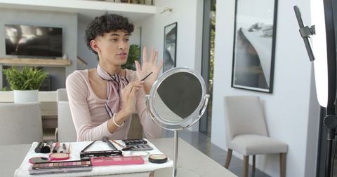 Male creator sharing makeup tutorial at home with stylish decor