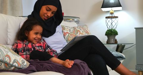 Mother and Daughter Bonding on Sofa with Digital Tablet