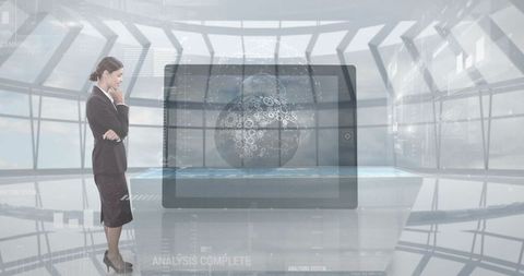 Businesswoman examines hologram globe in hi-tech office