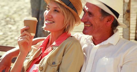 Happy Mature Couple Enjoying Coffee Sitting on City Bench