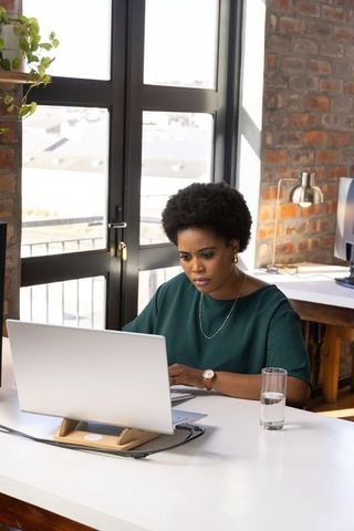 Focused Professional Woman Working on Laptop in Urban Office Space