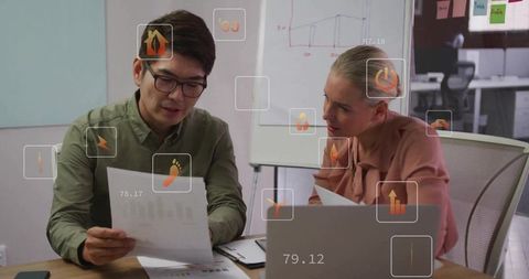 Colleagues Reviewing Data and Analyzing Metrics in Boardroom Meeting with Laptop and Charts