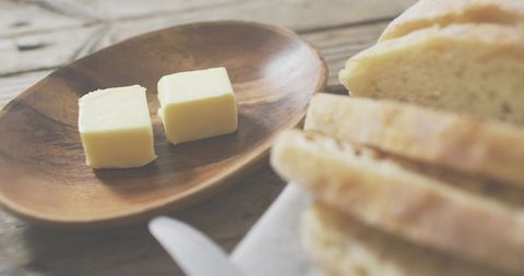 Two butter cubes resting on wooden dish with sliced bread rustic breakfast atmosphere