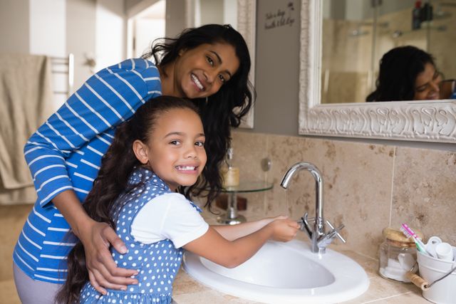 Mother and daughter washing hands together in bathroom, promoting hygiene and family bonding. Ideal for use in health campaigns, parenting blogs, family lifestyle articles, and advertisements focusing on cleanliness and hygiene.
