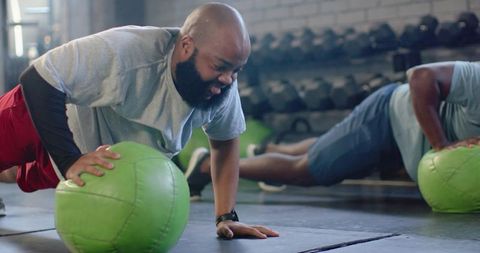African american men doing single-arm pushups with medicine balls partner workout