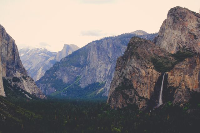 Majestic view of Yosemite National Park with towering cliffs and a flowing waterfall. Ideal for travel blogs, adventure articles, nature documentaries, and National Park promotional materials.