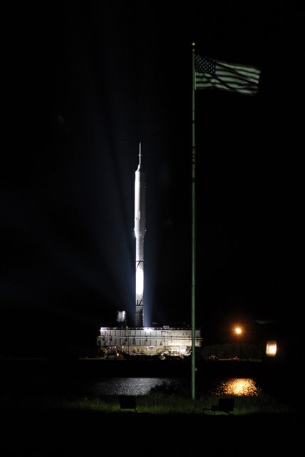 CAPE CANAVERAL, Fla. - The American flag waves as the Ares I-X rocket passes by on its slow trek to Launch Pad 39B at NASA's Kennedy Space Center in Florida. The rocket, riding atop a crawler-transporter, began the 4.2-mile journey at 1:39 a.m. EDT.    The transfer of the pad from the Space Shuttle Program to the Constellation Program took place May 31. Modifications made to the pad include the removal of shuttle unique subsystems, such as the orbiter access arm and a section of the gaseous oxygen vent arm, along with the installation of three 600-foot lightning towers, access platforms, environmental control systems and a vehicle stabilization system.  Part of the Constellation Program, the Ares I-X is the test vehicle for the Ares I. The Ares I-X flight test is targeted for Oct. 27. For information on the Ares I-X vehicle and flight test, visit http://www.nasa.gov/aresIX. Photo credit: NASA/Kim Shiflett