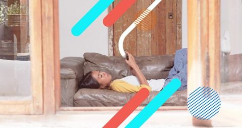 Young Chinese Woman Relaxing on Leather Sofa Scrolling Smartphone Rustic Wooden Home