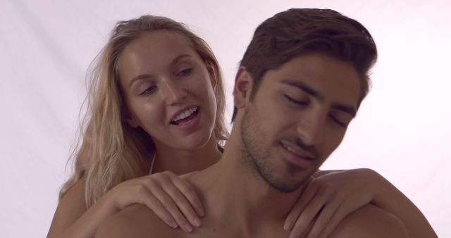 Blonde girl giving her boyfriend a shoulder rub at home in bedroom
