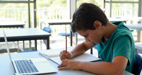 Young Boy Studying with Laptop Focused on Schoolwork - Download Free Stock Images Pikwizard.com